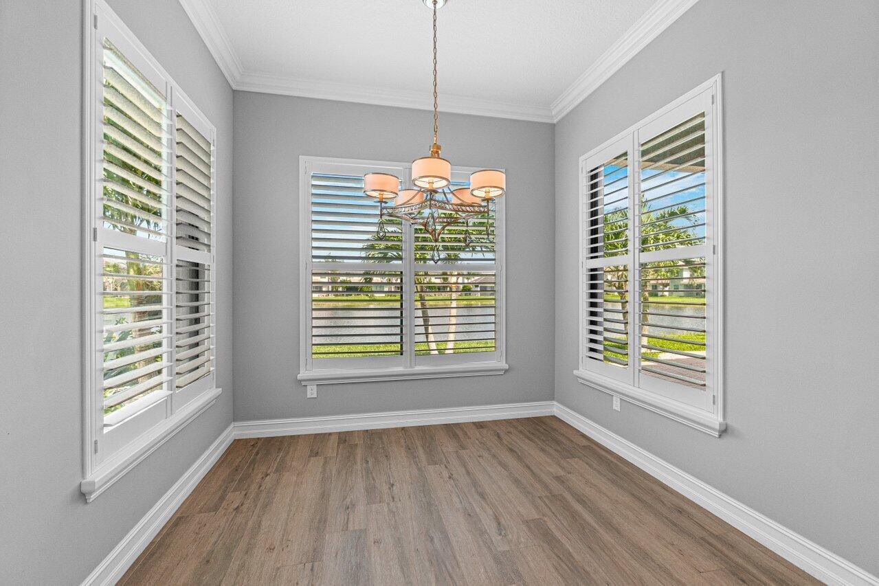 A dining area with light gray walls, wood-look flooring, a chandelier, and plantation shutters — 14131 Rock Salt Road, Delray Beach FL 33446, DELRAY BEACH, FL