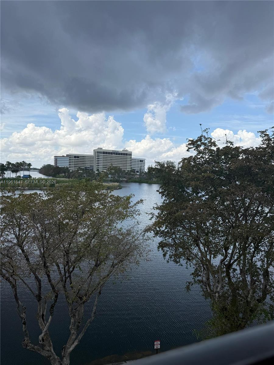 A view of a lake and a large hotel building framed by trees — 4805 NW 7th St # 15, Miami FL 33126, MIAMI, FL