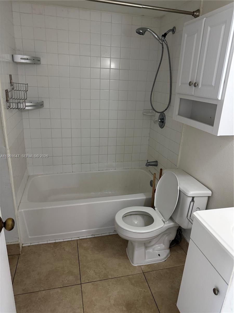 A bathroom features a white tiled bathtub, a toilet, and a white wall cabinet — 4805 NW 7th St # 15, Miami FL 33126, MIAMI, FL