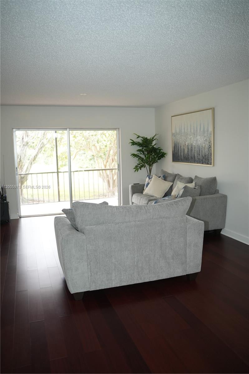 A living room features gray sofas, dark wood flooring, and a sliding glass door — 6001 N Falls Cir Dr # 203, Lauderhill FL 33319, LAUDERHILL, FL