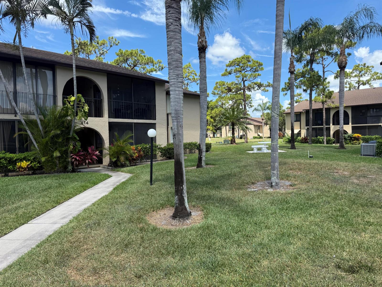 A two-story apartment building with arched entryways and palm trees on a grassy lawn — 414 Pine Glen Lane # 1, FL 33463, FL