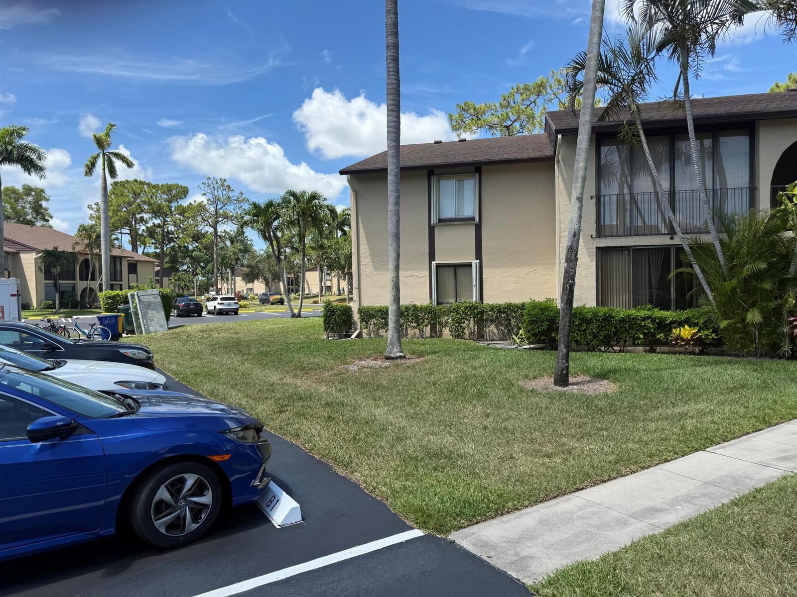 A two-story apartment building with a parking lot and palm trees in the foreground — 414 Pine Glen Lane # 1, FL 33463, FL
