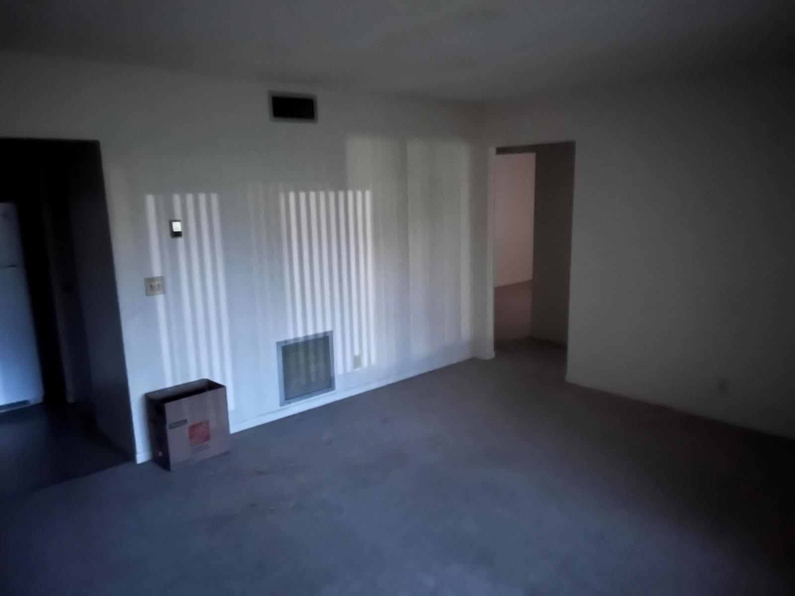 An empty room with gray carpet, white walls, a vent, and a doorway to another room — 414 Pine Glen Lane # 1, FL 33463, FL