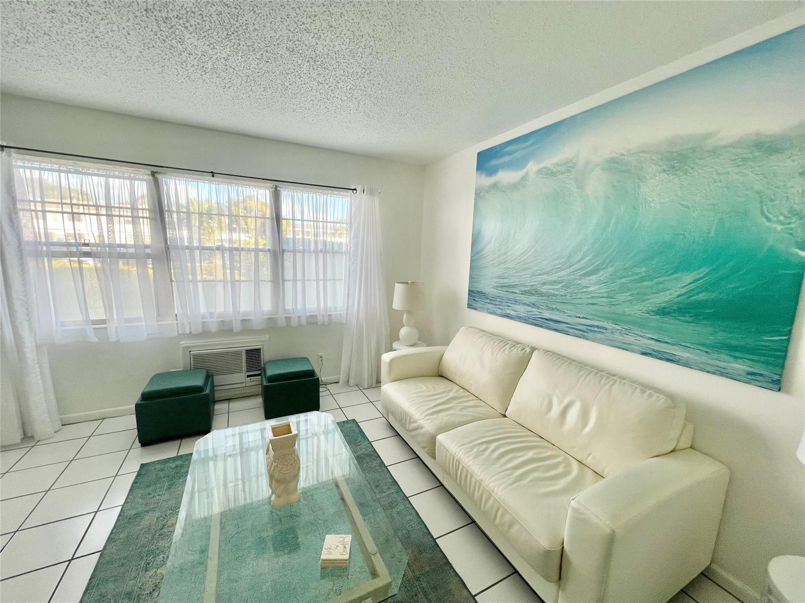 A living room features a white sofa, a large wave wall art, and tile flooring — 266 Oakridge P # 266, Deerfield Beach FL 33442, DEERFIELD BEACH, FL