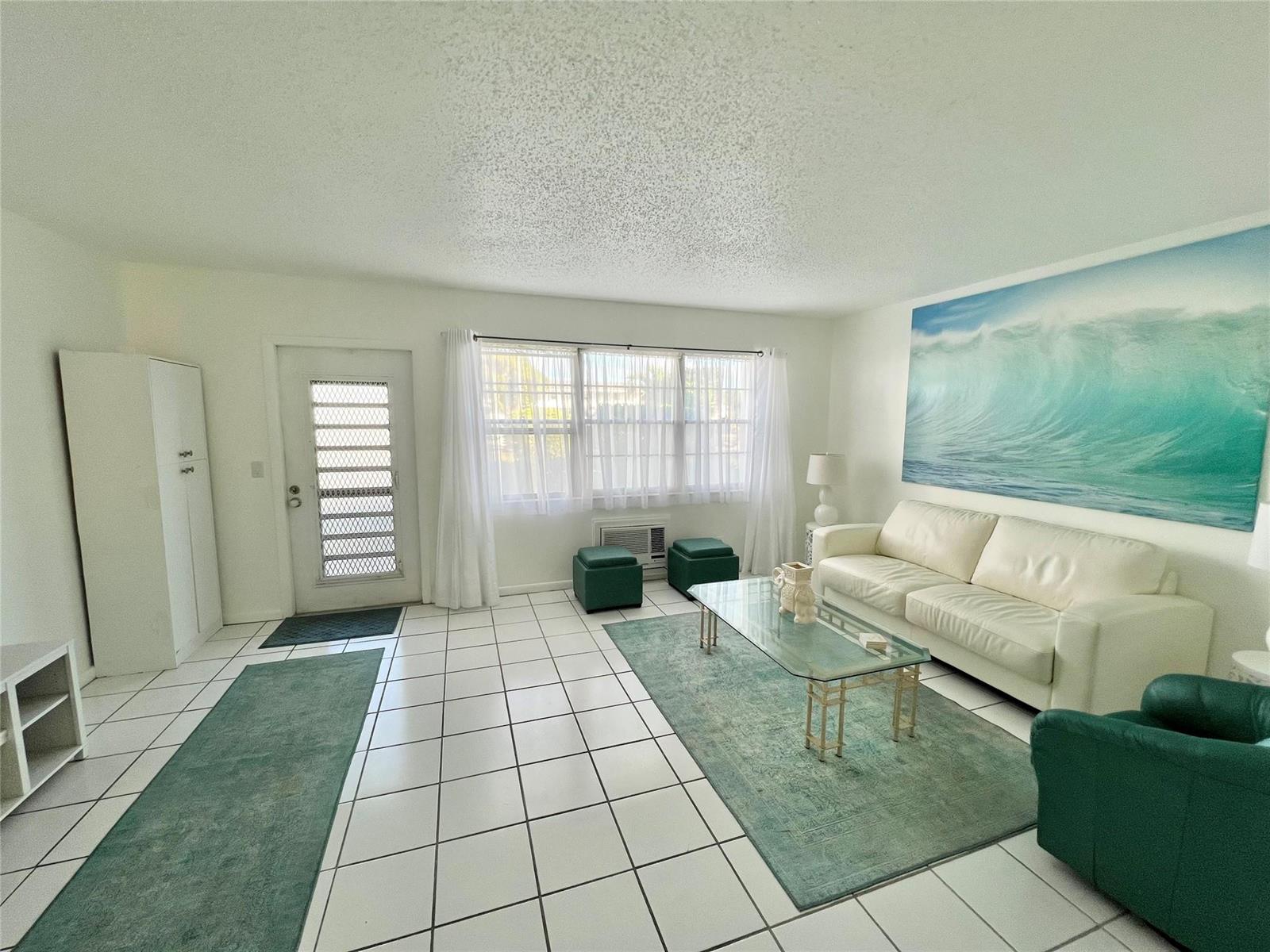 A living room features white tile floors, a white sofa, and a large ocean wall mural — 266 Oakridge P # 266, Deerfield Beach FL 33442, DEERFIELD BEACH, FL