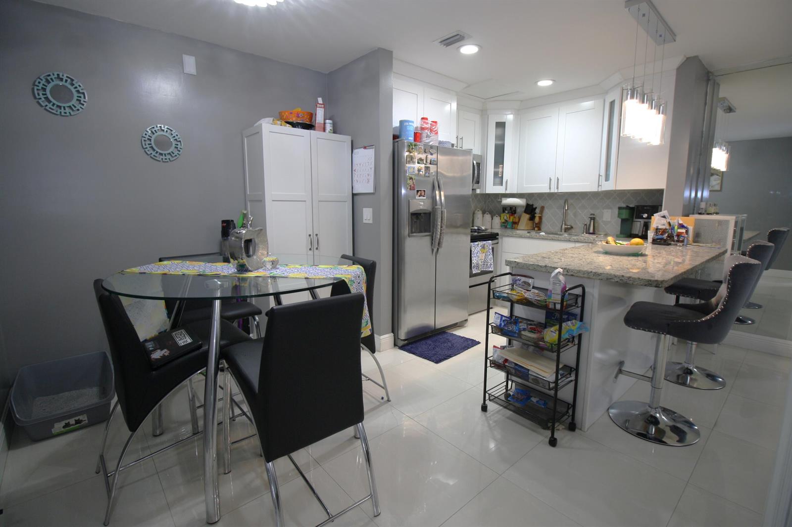 A kitchen features white cabinetry, granite countertops, stainless steel appliances, and a glass dining table — 6575 W 27th Court # 46, Hialeah FL 33016, HIALEAH, FL