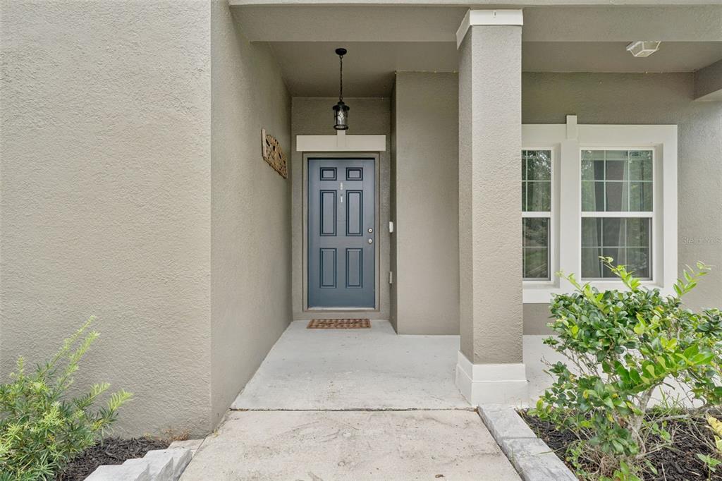 A covered entryway features a blue front door, a hanging light fixture, and concrete steps — 4080 GOLDEN WILLOW CIRCLE, APOPKA, FL