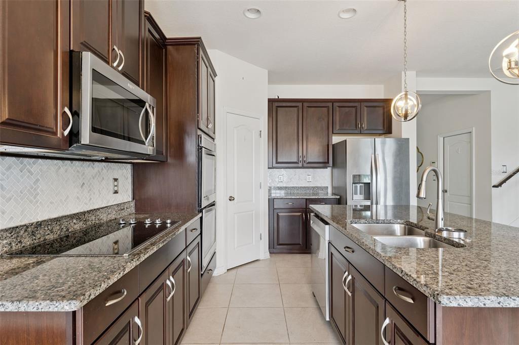 A kitchen with dark wood cabinets, granite countertops, stainless steel appliances, and a center island — 4080 GOLDEN WILLOW CIRCLE, APOPKA, FL
