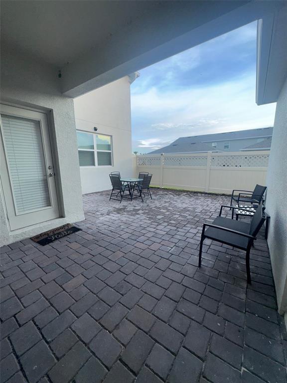A paved patio features outdoor furniture and a white privacy fence under a covered porch — 1920 TOHOQUA BOULEVARD, KISSIMMEE, FL