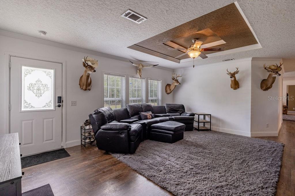 A living room features a dark leather sectional, a gray rug, and several deer head mounts — 24821 OLD DEER ROAD, PAISLEY, FL