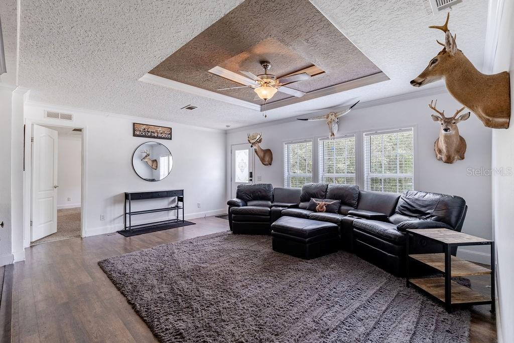 A living room features a dark leather sectional, a textured area rug, and several taxidermy mounts — 24821 OLD DEER ROAD, PAISLEY, FL