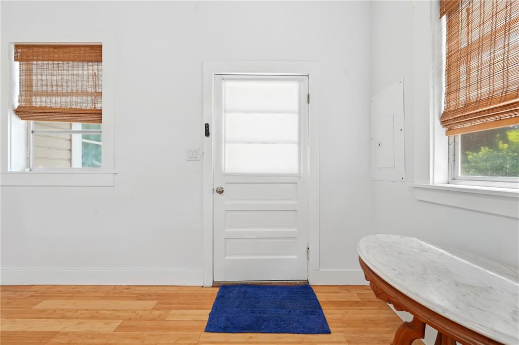 A room with white walls, wood flooring, a central door, and two windows with shades — 128 N LAKEVIEW DRIVE, LAKE HELEN, FL