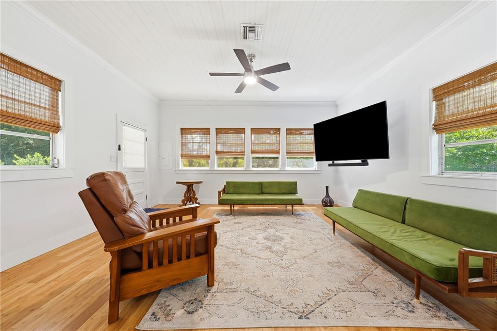 A living room features white walls, hardwood floors, green sofas, and a brown leather chair — 128 N LAKEVIEW DRIVE, LAKE HELEN, FL