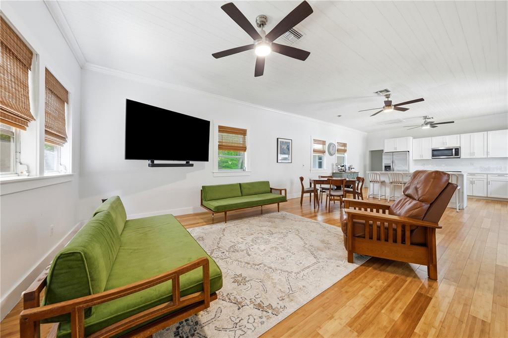 A living room with two green sofas, a brown recliner, and an open kitchen area — 128 N LAKEVIEW DRIVE, LAKE HELEN, FL
