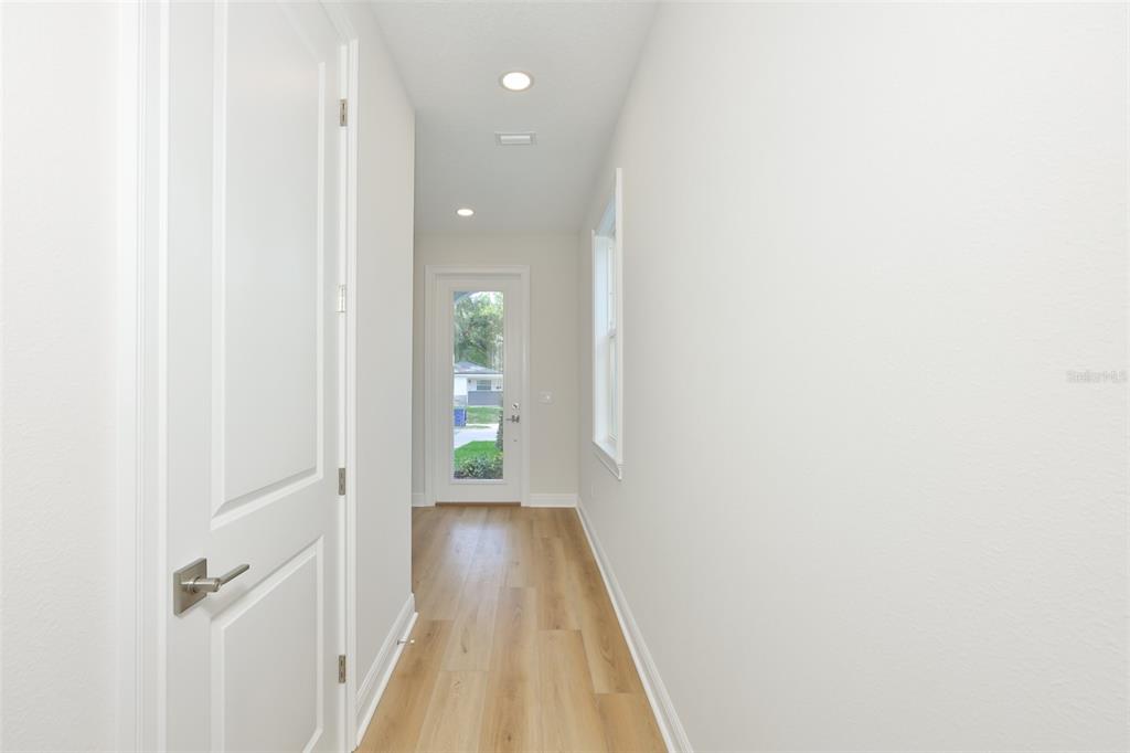A hallway with light wood flooring, white walls, a side window, and a glass-paneled door — 1913 W BEACH STREET, TAMPA, FL