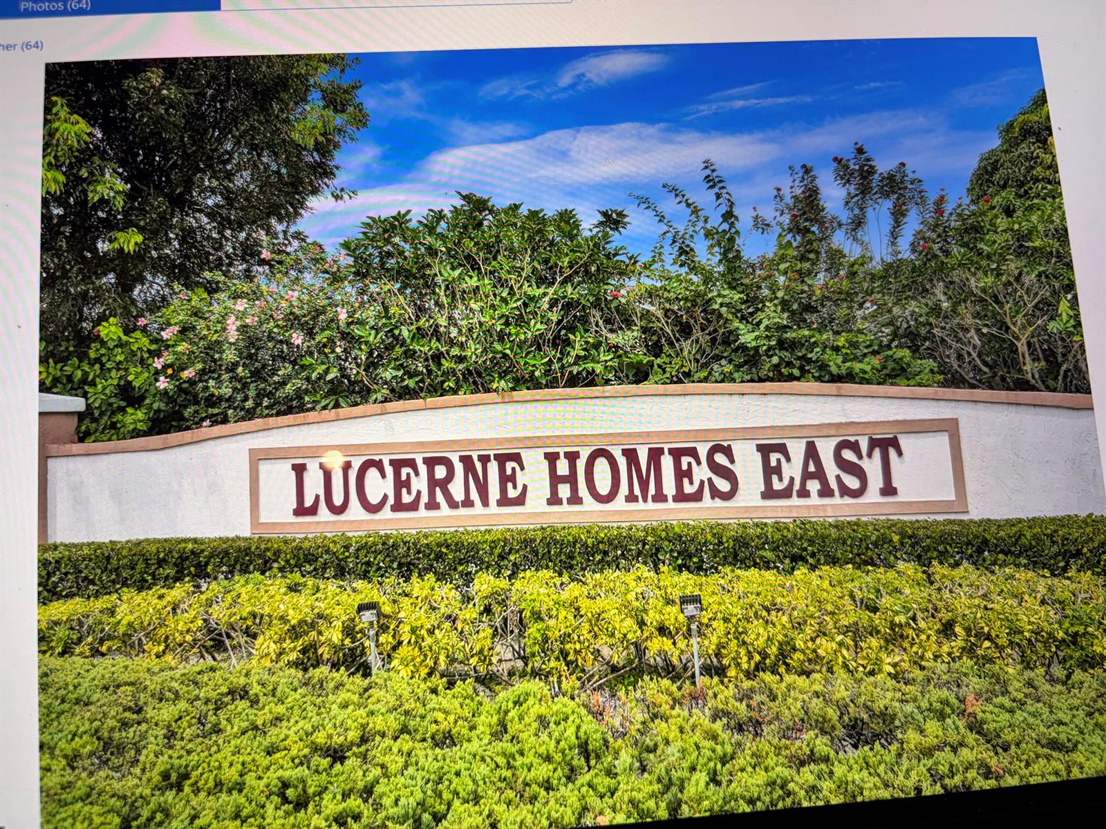 A sign for Lucerne Homes East stands behind a manicured hedge and lush greenery — 6309 Silver Moon Lane, FL 33463, FL