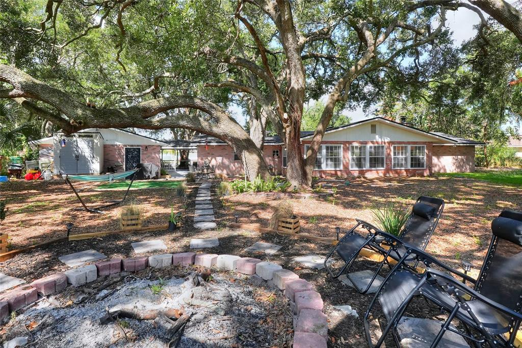 A backyard features a fire pit, lounge chairs, a hammock, and a brick house exterior — 5315 POST LANE, LAKELAND, FL