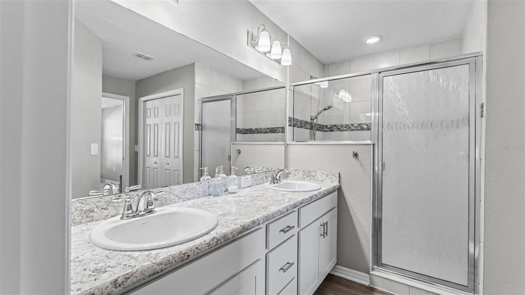 A bathroom features a double vanity with a granite countertop and a glass-enclosed shower — 3863 WILLOW RIDGE DRIVE, LAKELAND, FL