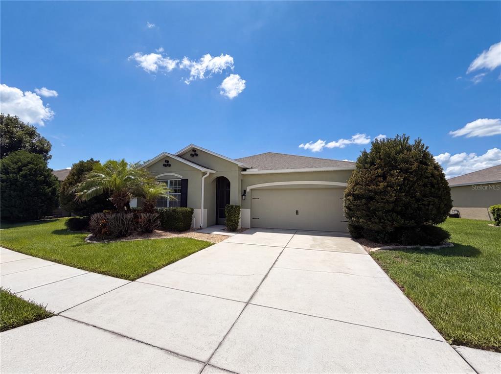 A single-story house with a two-car garage, a concrete driveway, and landscaped front yard — 5811 MARSH LANDING DRIVE, WINTER HAVEN, FL