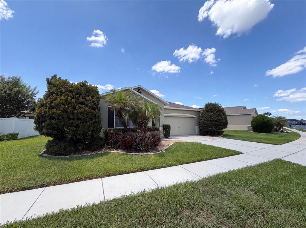 A single-story suburban house with a tan exterior, a two-car garage, and landscaped front yard — 5811 MARSH LANDING DRIVE, WINTER HAVEN, FL