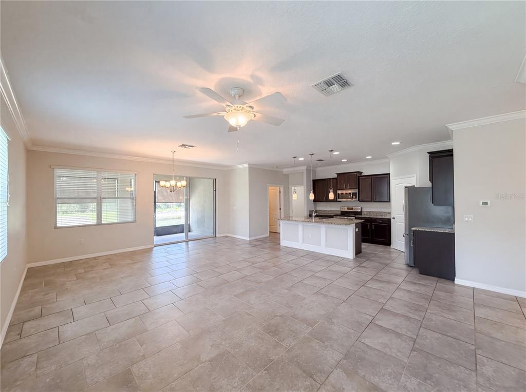 A spacious open-concept living area features tile flooring, a kitchen island, and sliding glass doors — 5811 MARSH LANDING DRIVE, WINTER HAVEN, FL