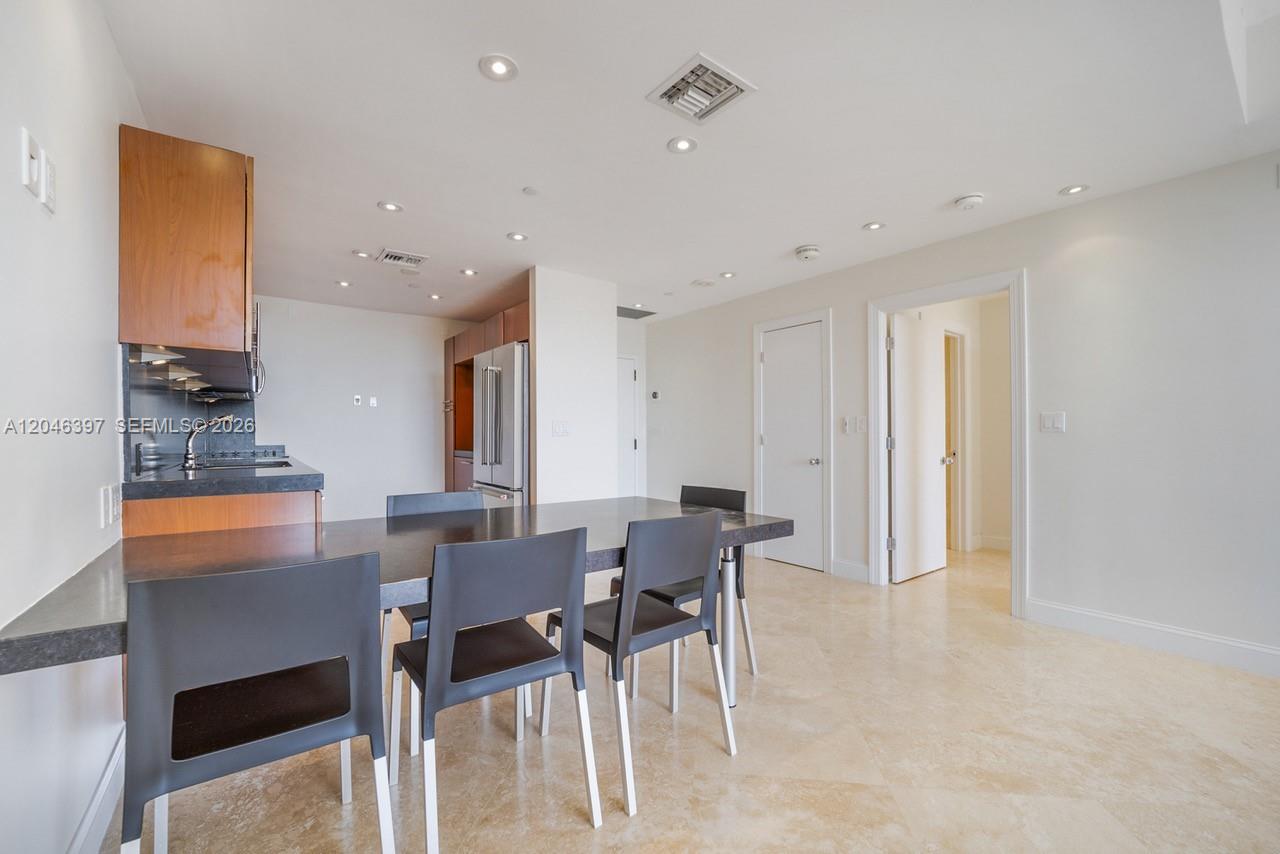 A kitchen with wooden cabinets and a dining table with four chairs on tile floors — 151 Crandon Blvd # 439, Key Biscayne FL 33149, KEY BISCAYNE, FL