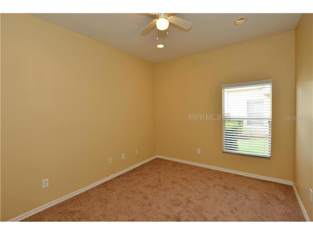 An empty bedroom features tan walls, beige carpeting, a ceiling fan, and a single window — 3132 SAGO POINT COURT, LAND O LAKES, FL