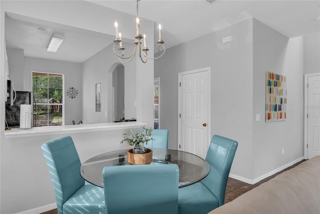A dining area features a glass-topped table with four blue chairs under a chandelier — 457 LA MIRAGE STREET, DAVENPORT, FL