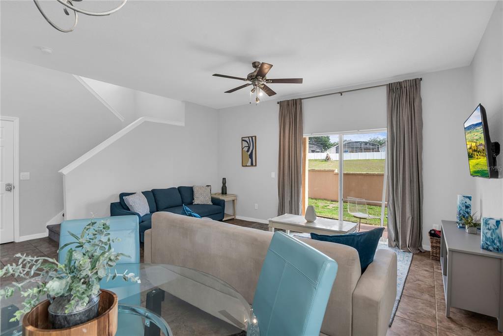 A living room features a blue sofa, a beige sofa, and sliding glass doors — 457 LA MIRAGE STREET, DAVENPORT, FL