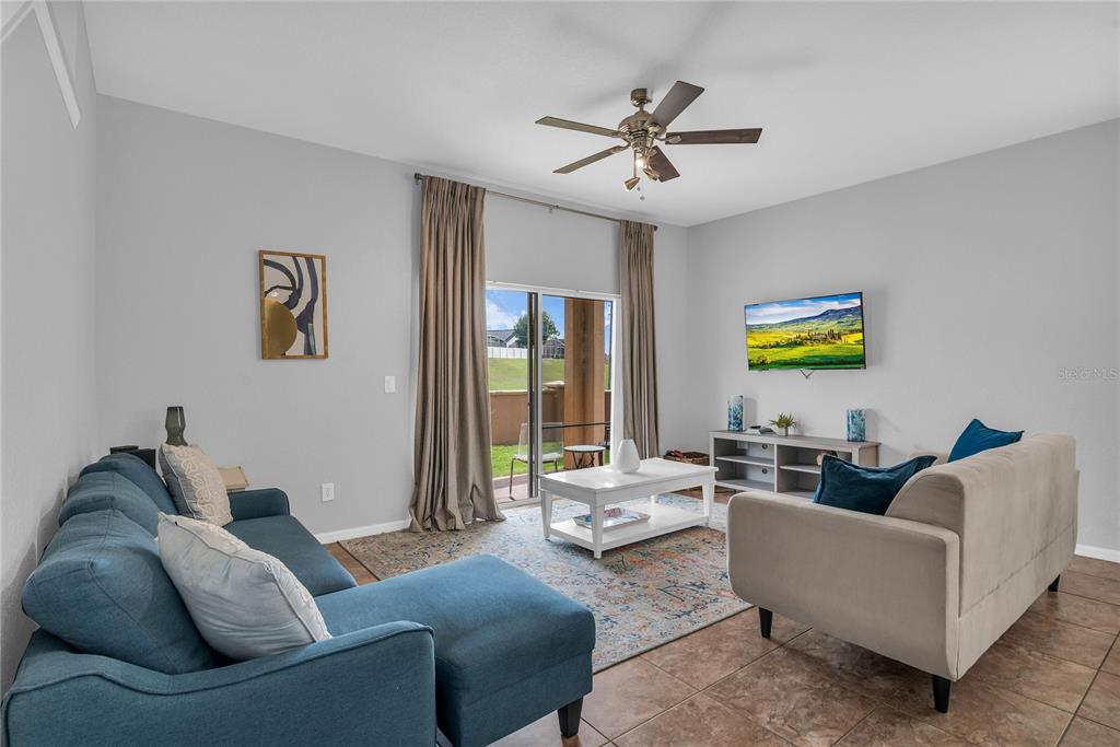 A living room features a blue sectional, a beige sofa, a coffee table, and a television — 457 LA MIRAGE STREET, DAVENPORT, FL
