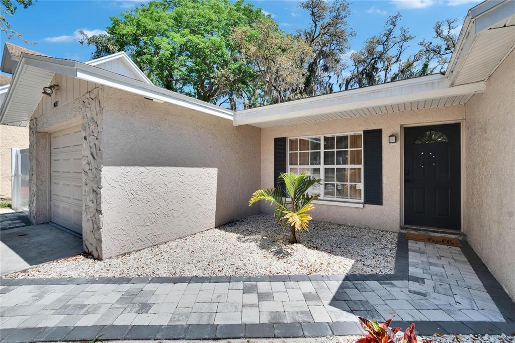 A single-story house exterior features a stone-accented garage, a gravel front yard, and a walkway — 9613 N 46TH STREET, TAMPA, FL
