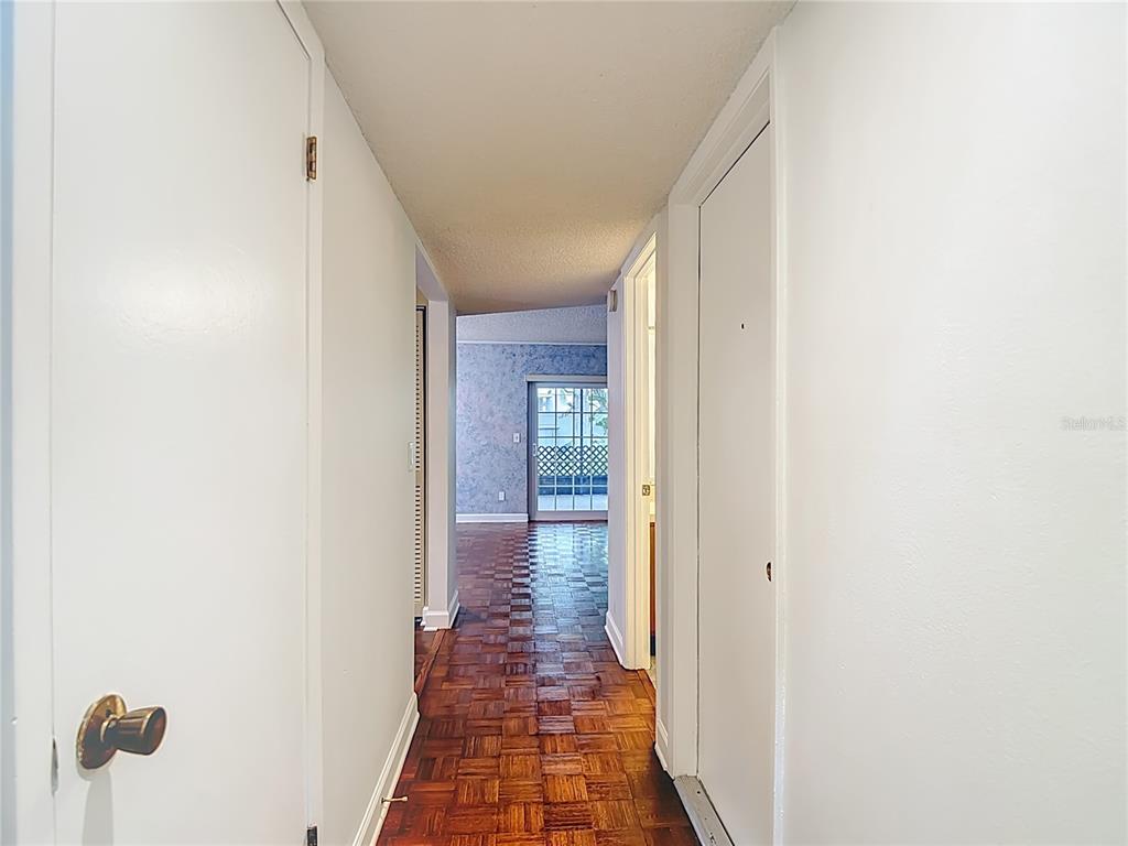 A hallway with parquet wood flooring leads to a room with a sliding glass door — 16851 LE CLARE SHORES DRIVE, TAMPA, FL