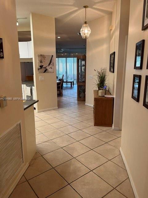 A tiled hallway leads to a dining area with a glass door and pendant lighting — 10136 Lombardy Dr, Tamarac FL 33321, TAMARAC, FL