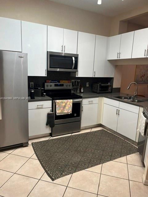 A kitchen features white cabinets, stainless steel appliances, and a patterned rug on tiled floors — 10136 Lombardy Dr, Tamarac FL 33321, TAMARAC, FL