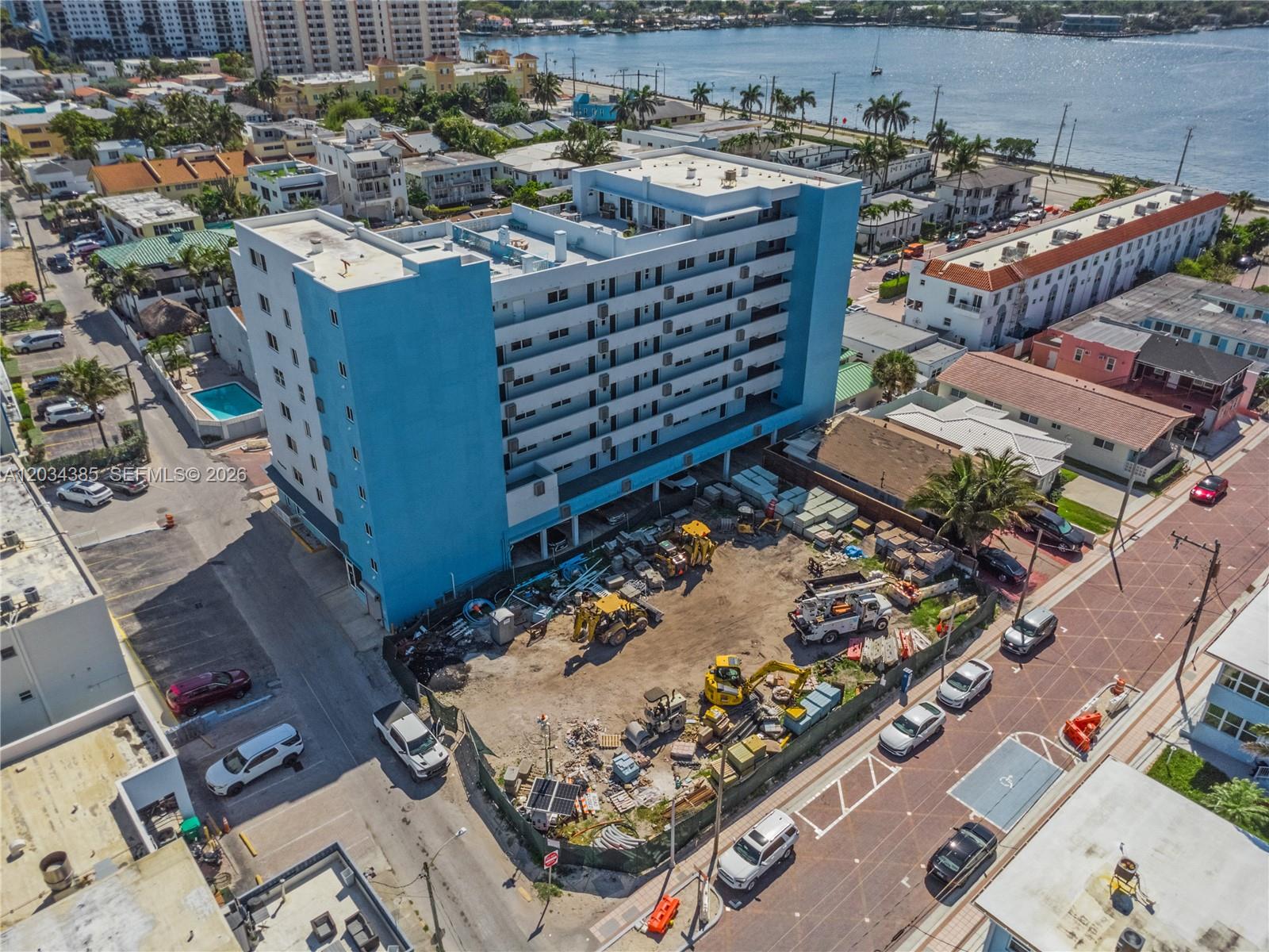 An aerial view shows a blue multi-story apartment building next to a construction site — 300 Van Buren St, Hollywood FL 33019, HOLLYWOOD, FL