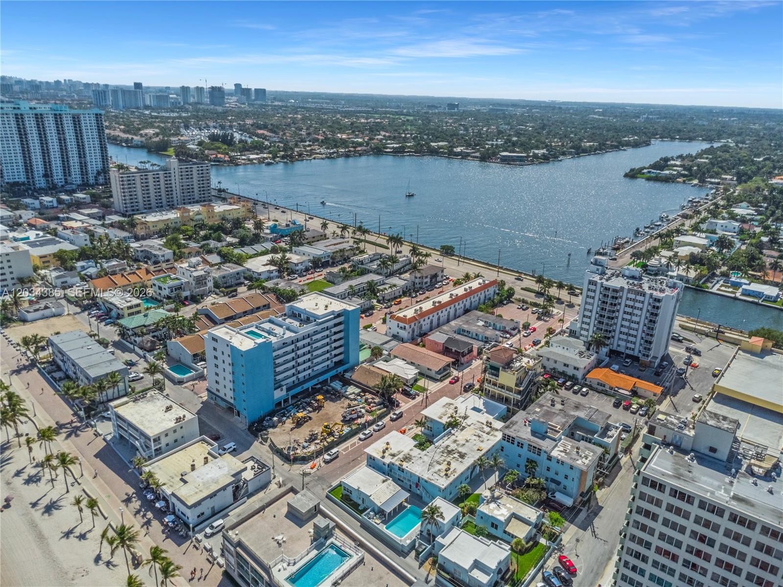 An aerial view shows a coastal neighborhood with apartment buildings, swimming pools, and a waterway — 300 Van Buren St, Hollywood FL 33019, HOLLYWOOD, FL