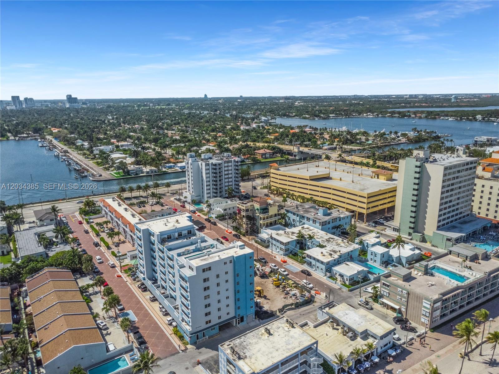 An aerial view shows a coastal neighborhood with apartment buildings, a parking garage, and waterways — 300 Van Buren St, Hollywood FL 33019, HOLLYWOOD, FL