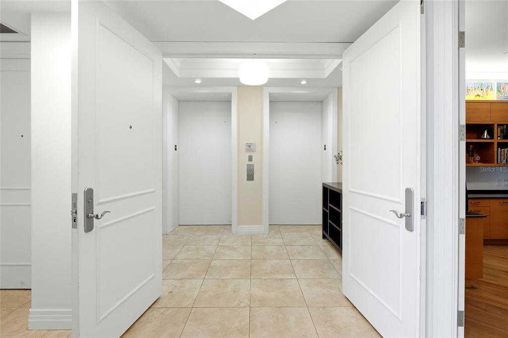 A tiled hallway features two white elevator doors and double doors opening into the space — 400 BEACH DRIVE NE UNIT 401, ST PETERSBURG, FL
