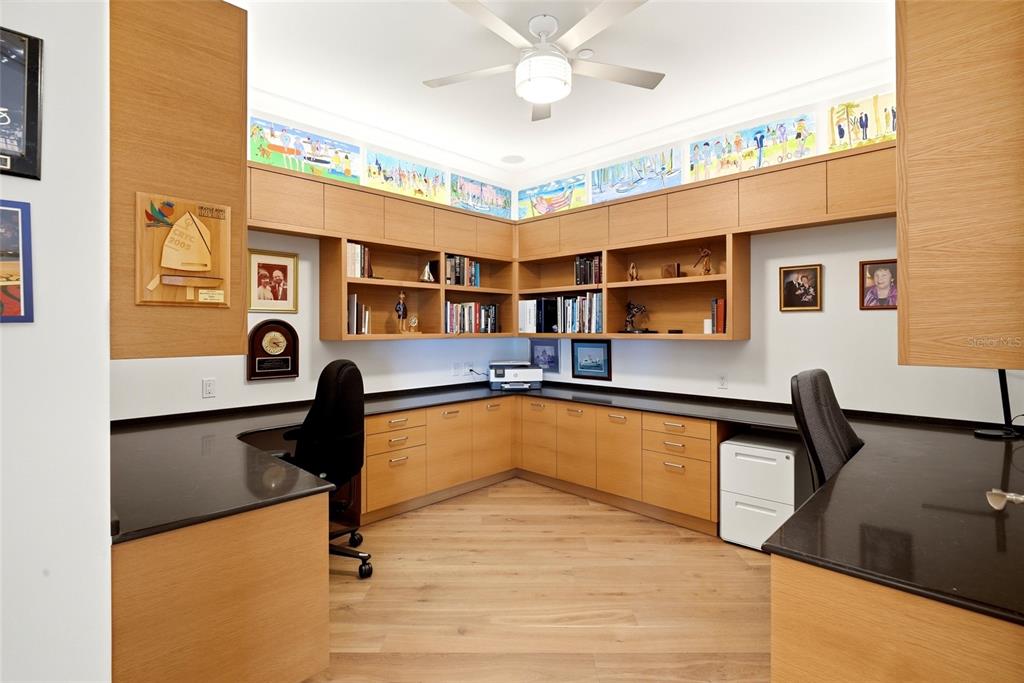 A home office features light wood cabinetry, a U-shaped desk with black countertops, and shelving — 400 BEACH DRIVE NE UNIT 401, ST PETERSBURG, FL