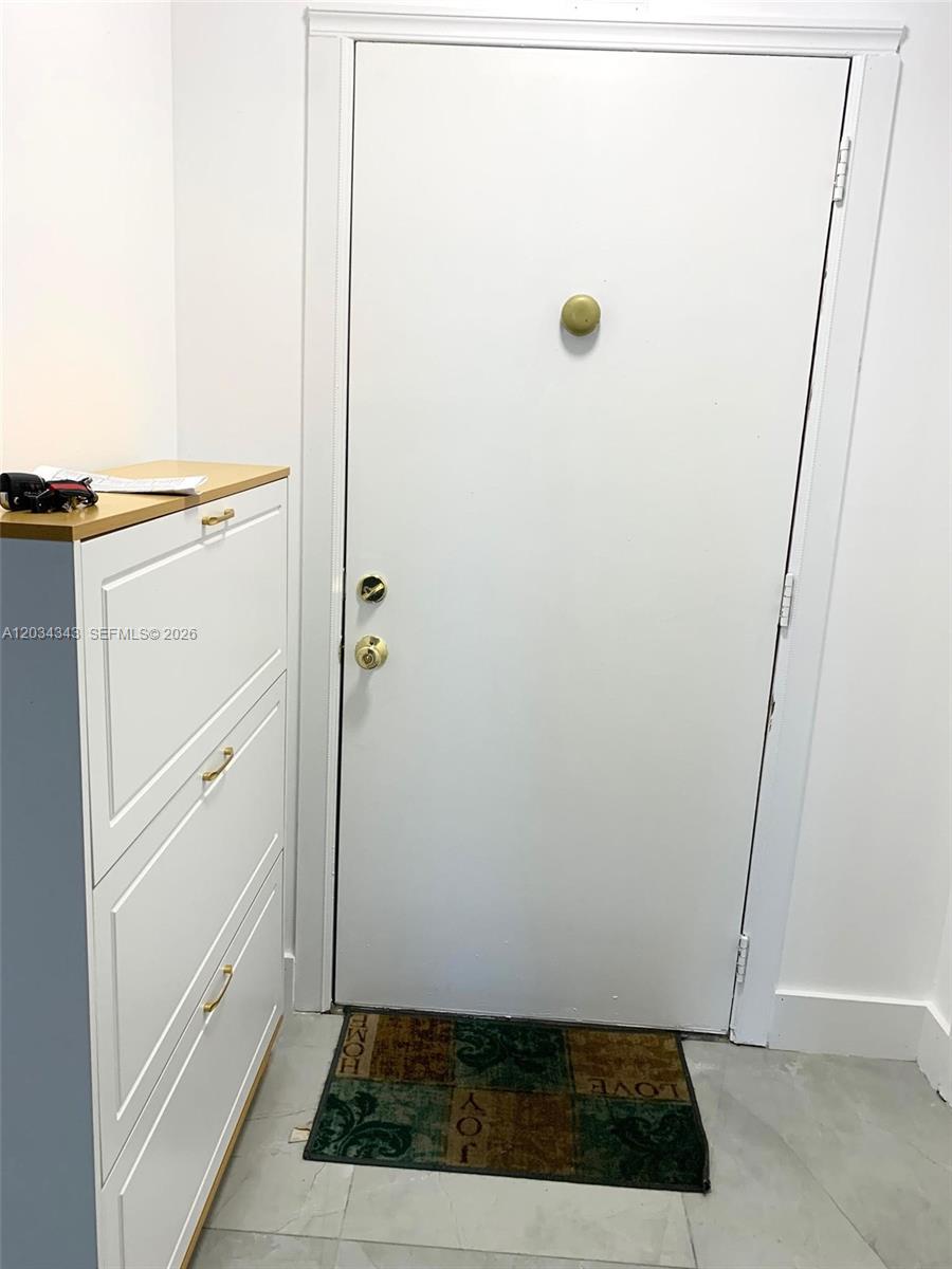 A white door with gold hardware stands next to a white shoe cabinet — 501 NE 14th Ave # 601, Hallandale Beach FL 33009, HALLANDALE BEACH, FL