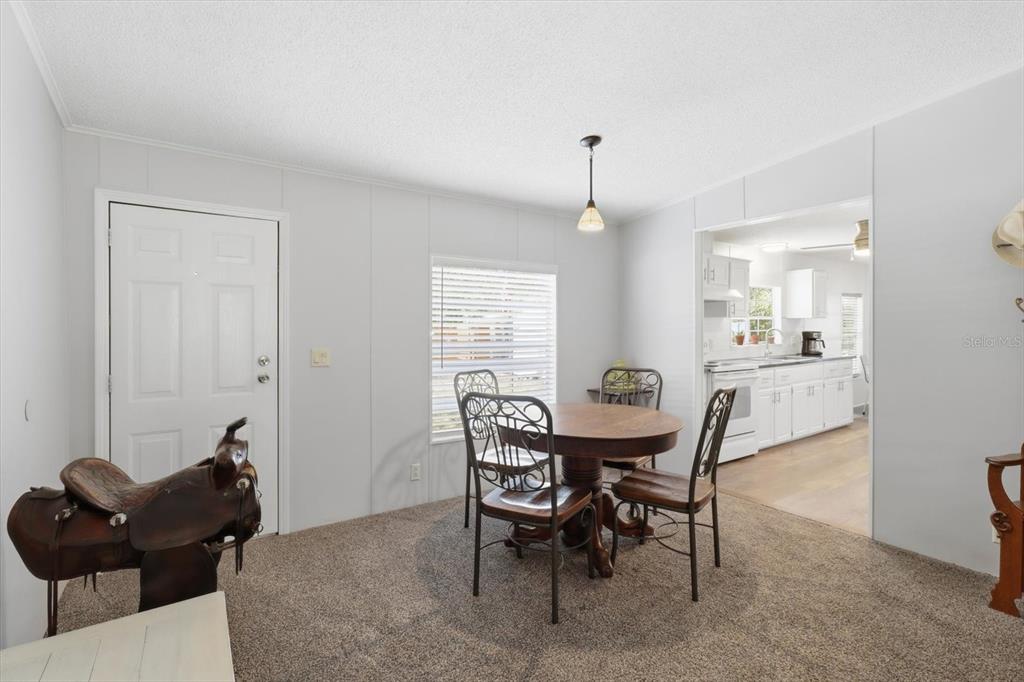 A dining area with carpeted flooring, a round wooden table, and an adjacent kitchen — 7298 S RAMA AVENUE, LECANTO, FL