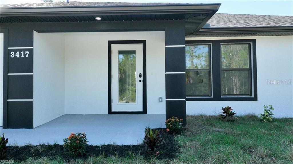The exterior of a modern house features a white facade with black trim and accents — 3417 57TH STREET W, LEHIGH ACRES, FL