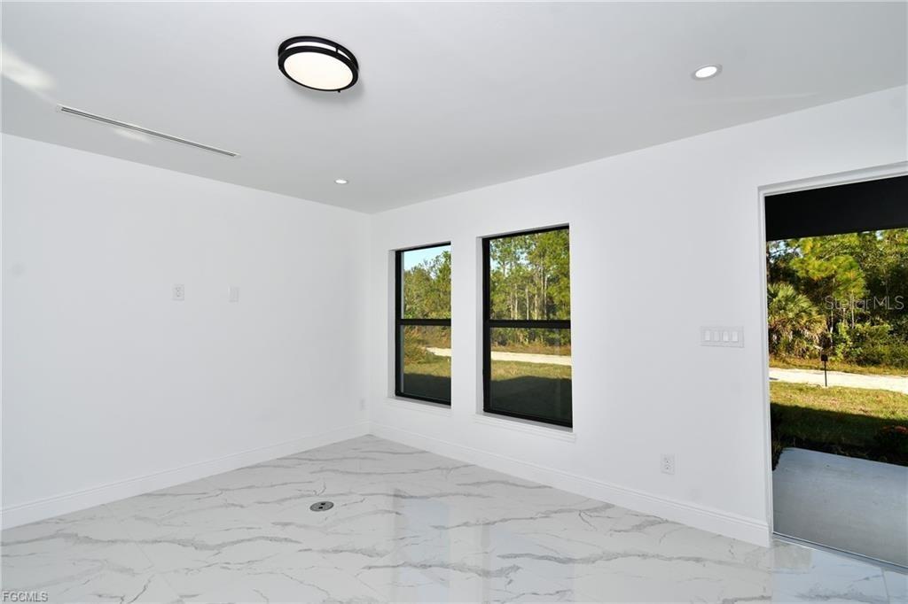 A bright room features white walls, marble-patterned tile flooring, black-framed windows, and a ceiling light — 3417 57TH STREET W, LEHIGH ACRES, FL