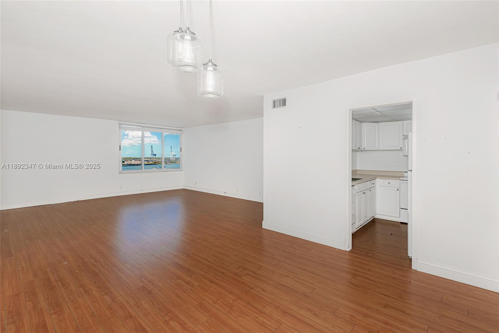 An empty living room with wood-look flooring features a view of a harbor through windows — 1200 West Ave # 1531, Miami Beach FL 33139, MIAMI BEACH, FL