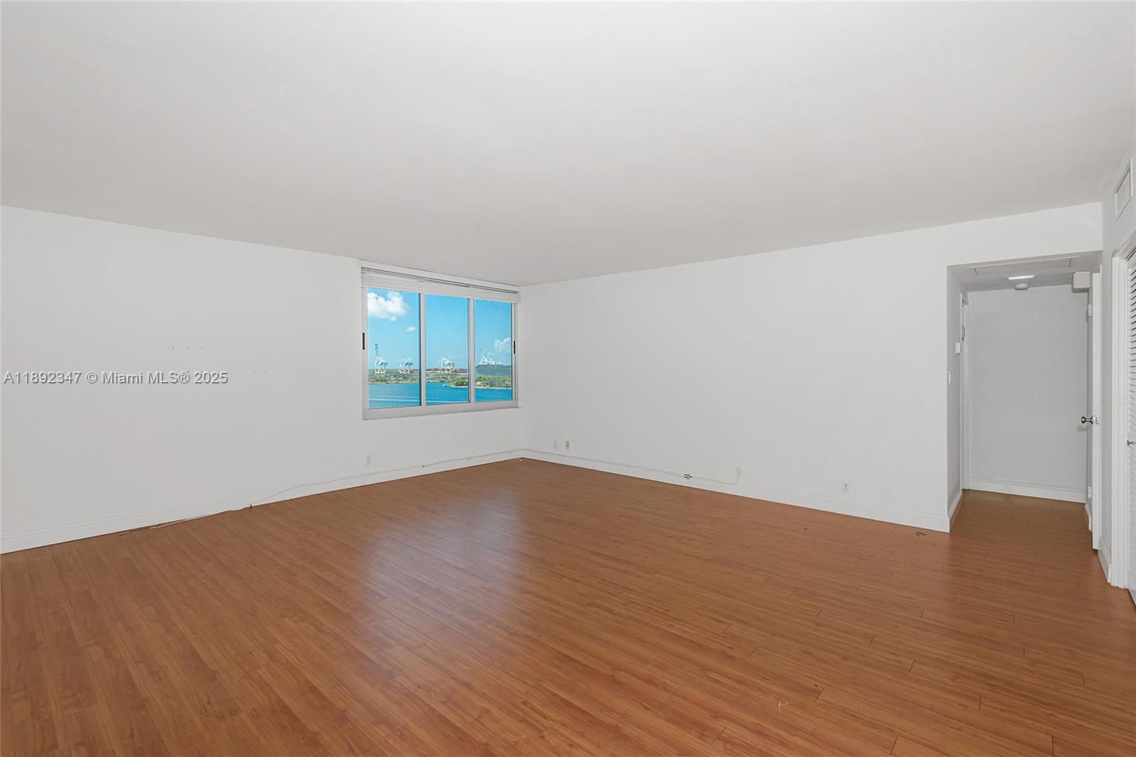 An empty room with wood-look flooring, white walls, and a window overlooking the water — 1200 West Ave # 1531, Miami Beach FL 33139, MIAMI BEACH, FL