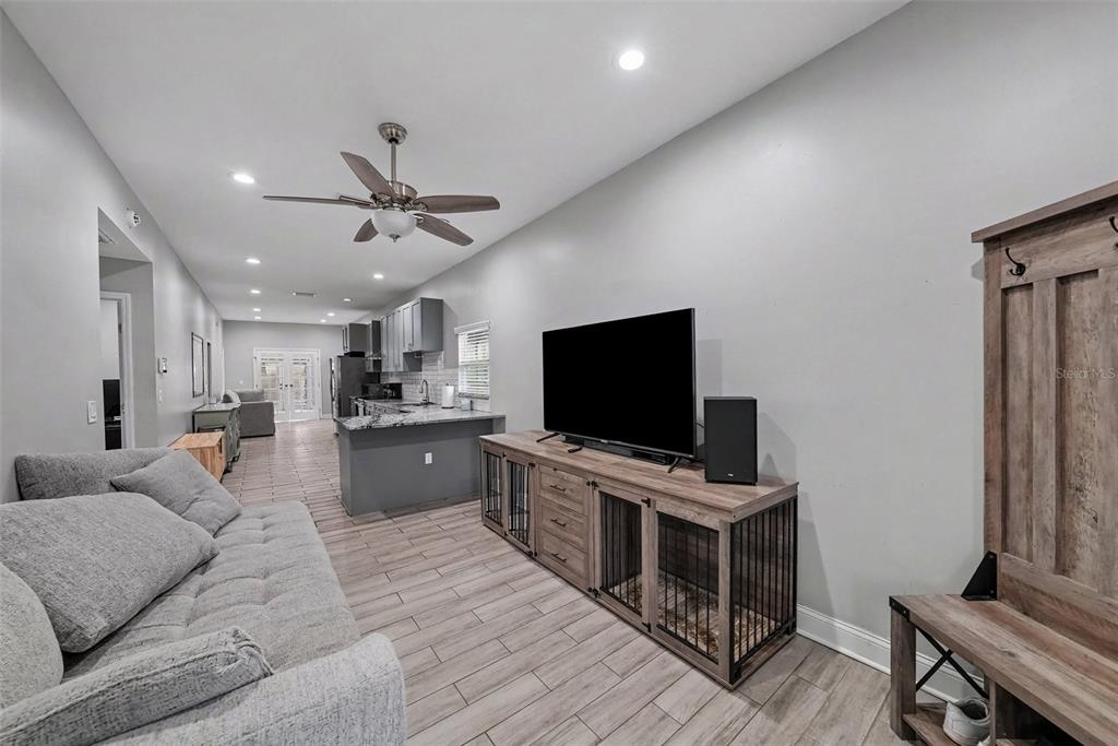 A living room features wood-look tile flooring, a gray sofa, and a media console with integrated kennels — 2341 W CHESTNUT STREET, TAMPA, FL