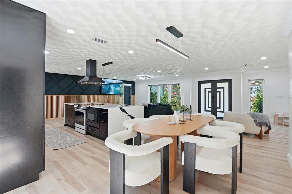 An open-concept kitchen and dining area features a textured ceiling, black cabinetry, and wood accents — 3931 W RIVERSIDE DRIVE, FORT MYERS, FL