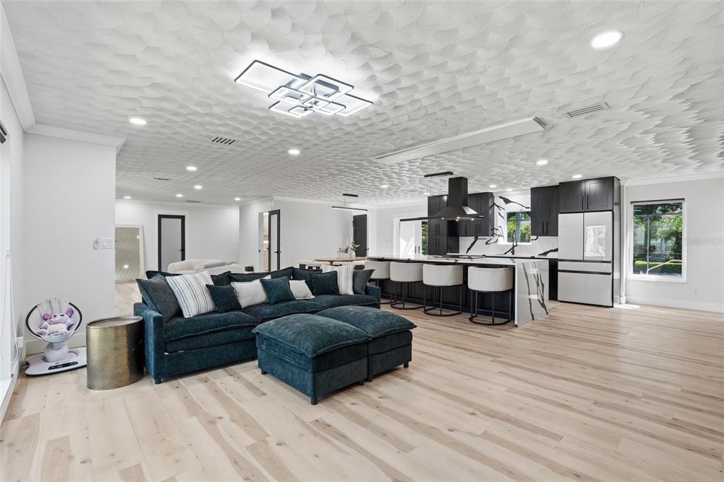 An open-concept living room and kitchen featuring a dark blue sectional, textured ceiling, and island — 3931 W RIVERSIDE DRIVE, FORT MYERS, FL