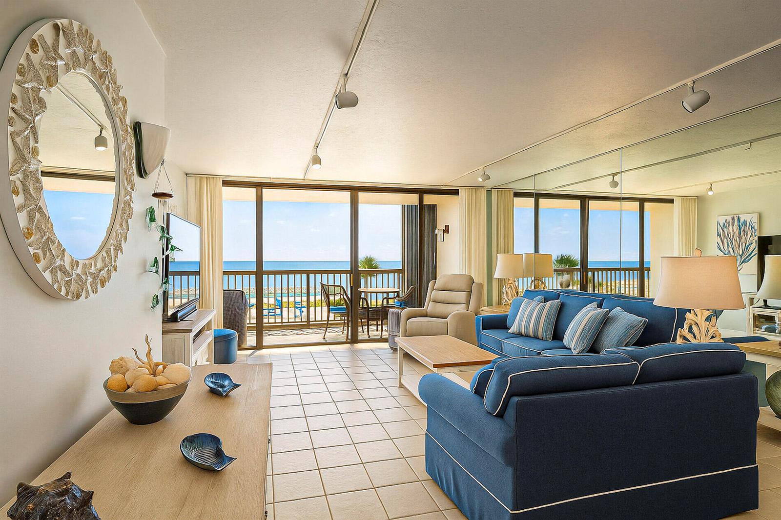 A living room with blue furniture, tiled floors, and a balcony overlooking the ocean — 4141 Ocean Drive # 403, Vero Beach FL 32963, VERO BEACH, FL