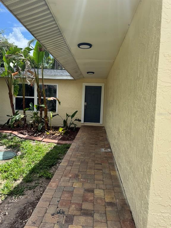 A paved walkway leads to a dark blue front door under a covered entryway — 3306 LAKE SAXON DRIVE, LAND O LAKES, FL